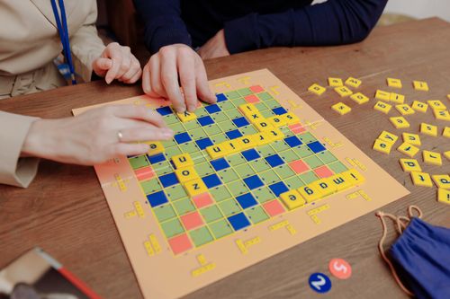 Free A close-up of people playing a word board game indoors, enhancing cognitive skills. Stock Photo