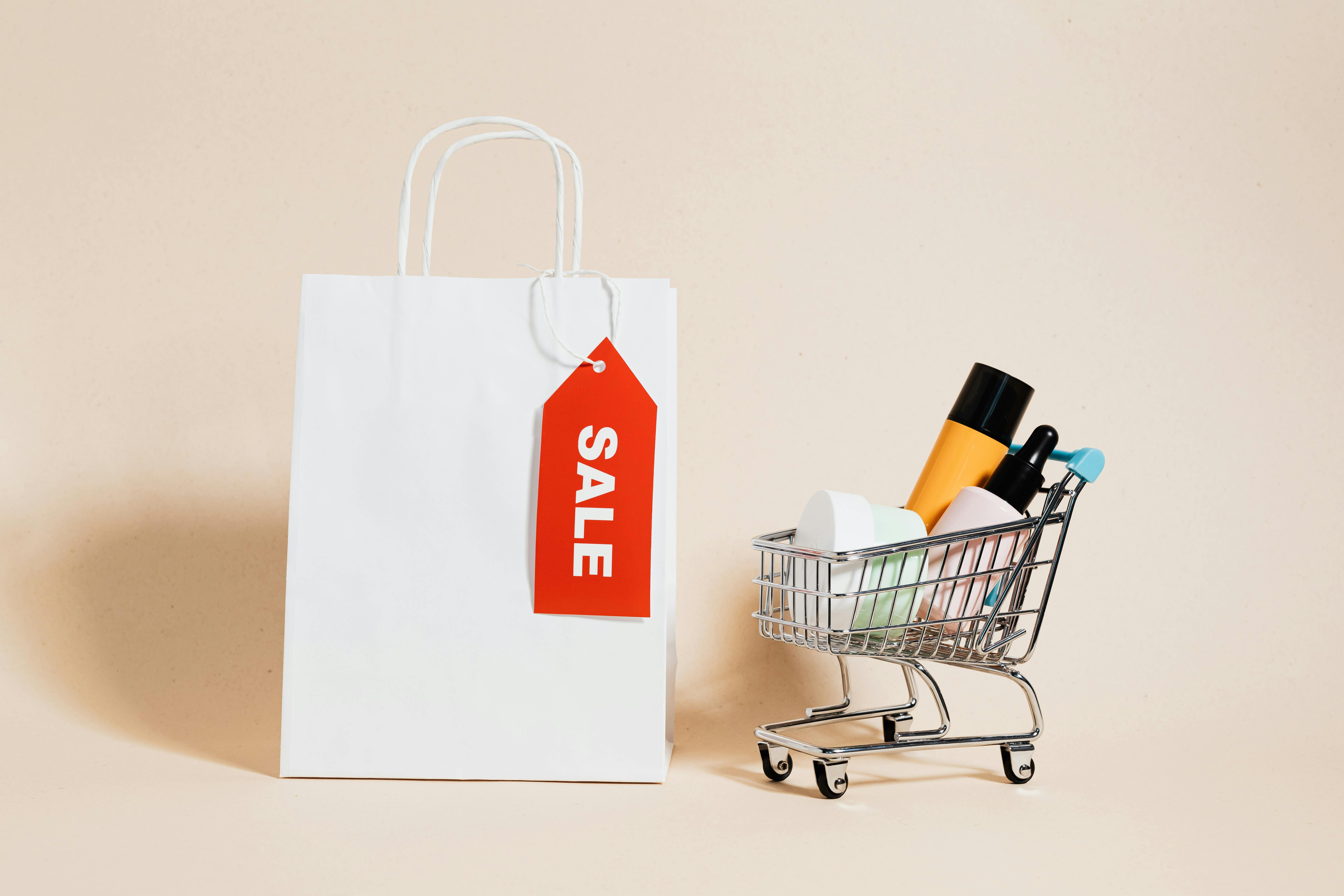 a white paper bag and shopping cart on beige background