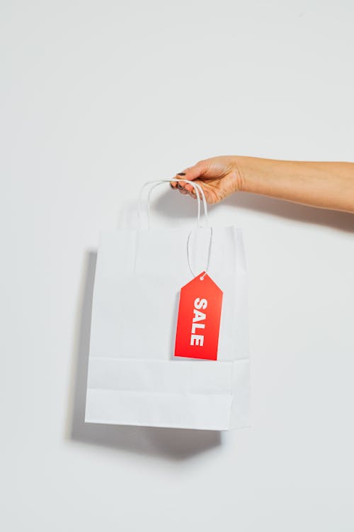 Free Person Holding a White Paper Bag With Sale Card Stock Photo