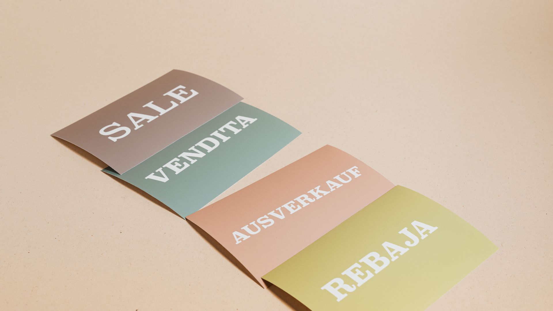 Business Cards: Your Ultimate Networking Tool 5 Four sale signs in different languages on a beige background, ideal for retail promotions — business cards