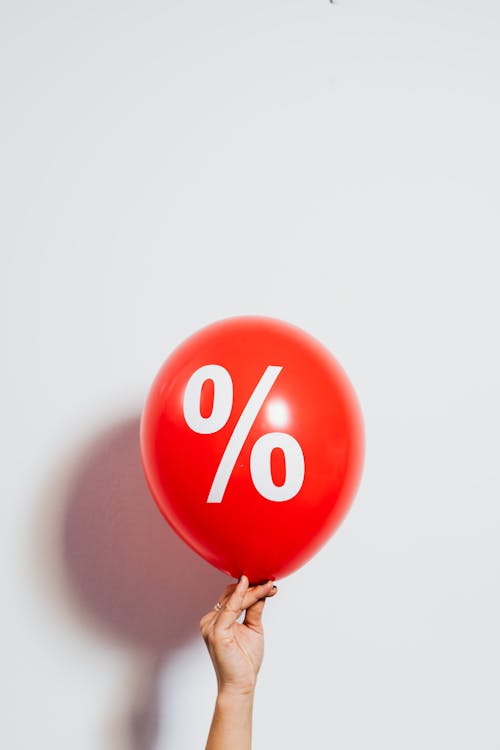 Person Holding a Red Balloon With Percentage Symbol