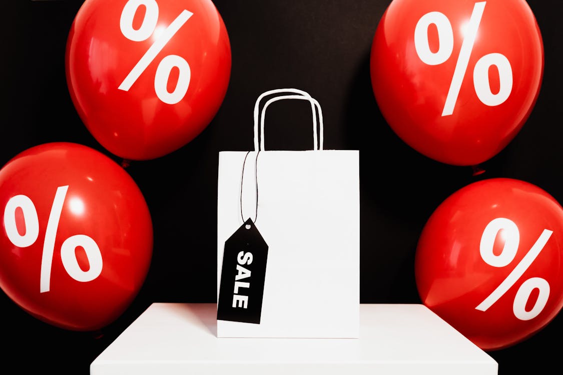 Free White Paper Bag Surrounded by Red Balloons Stock Photo