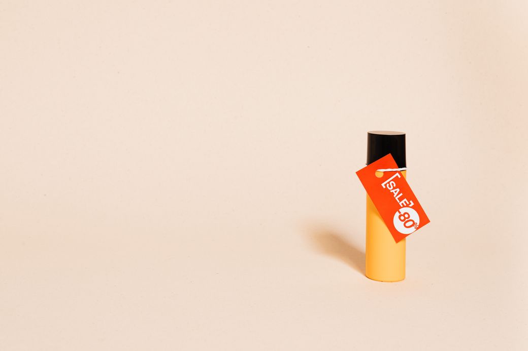 A sale tag hanging from a bottle on a warm cream backdrop — photo by kaboompics.com on Pexels