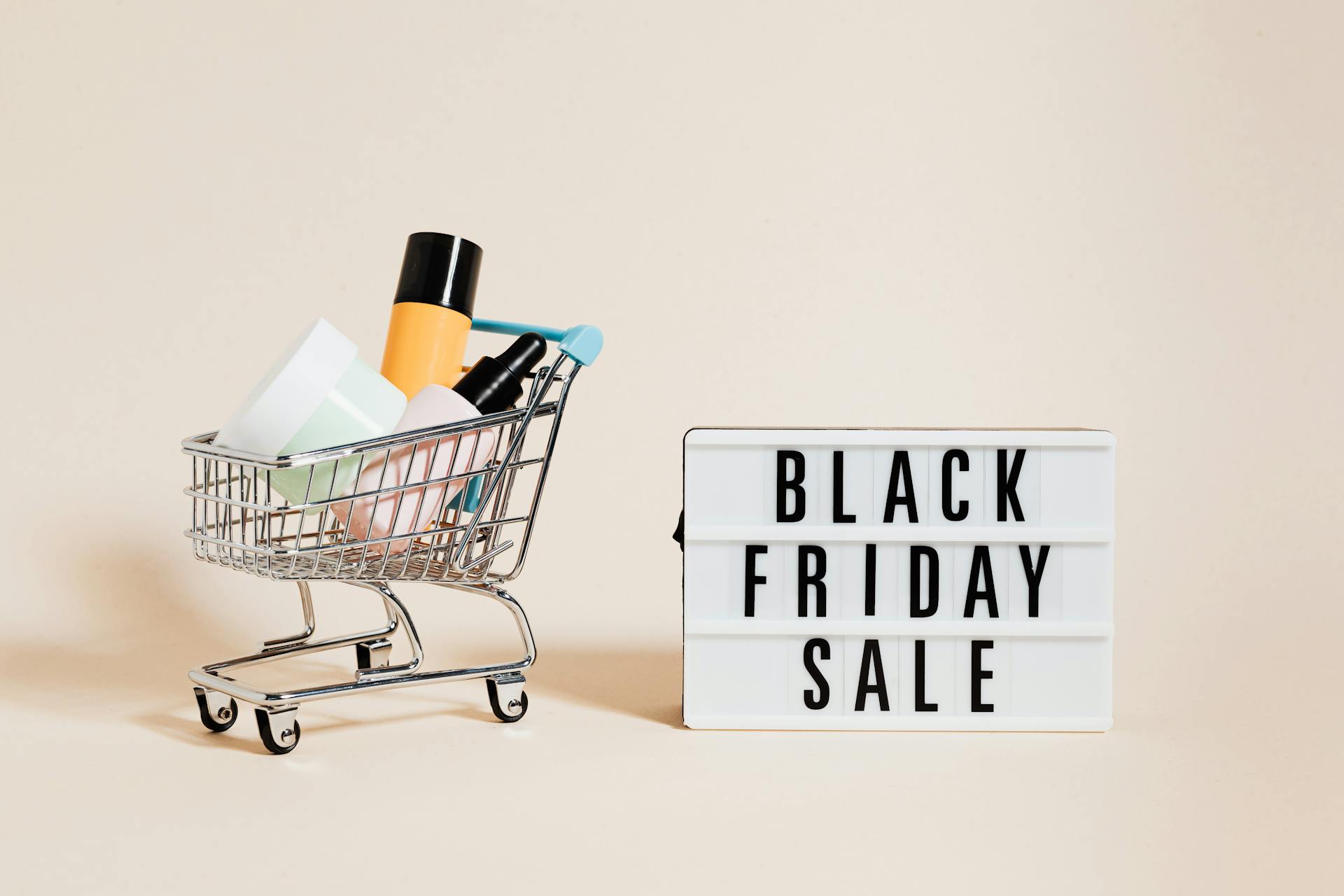 Products in a Shopping Cart Beside a Black Friday Sale Signage on Beige Background