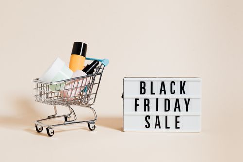 Free Stylish display of a mini shopping cart and a Black Friday sale sign on a beige background. Stock Photo