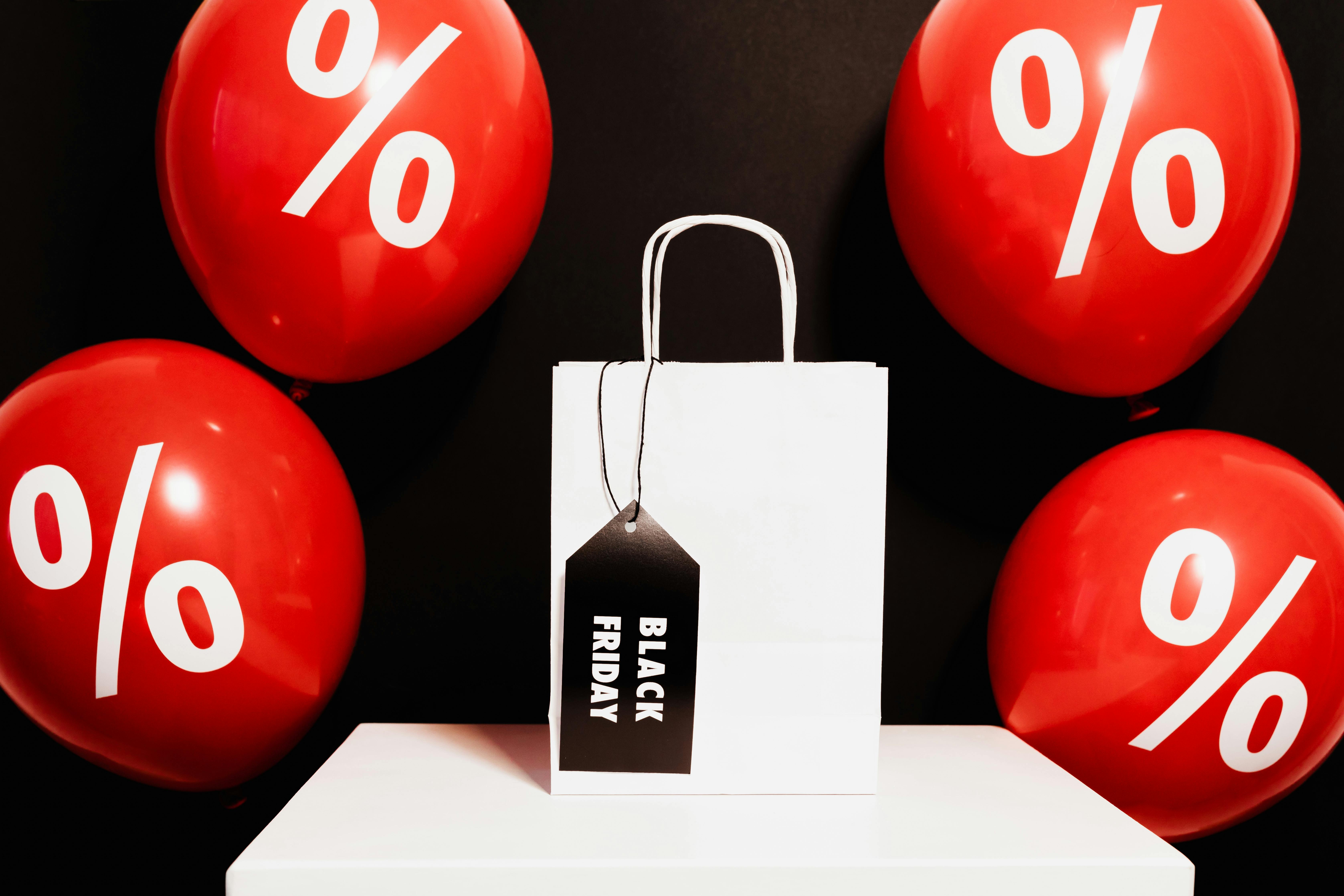 white paper bag surrounded by red balloons