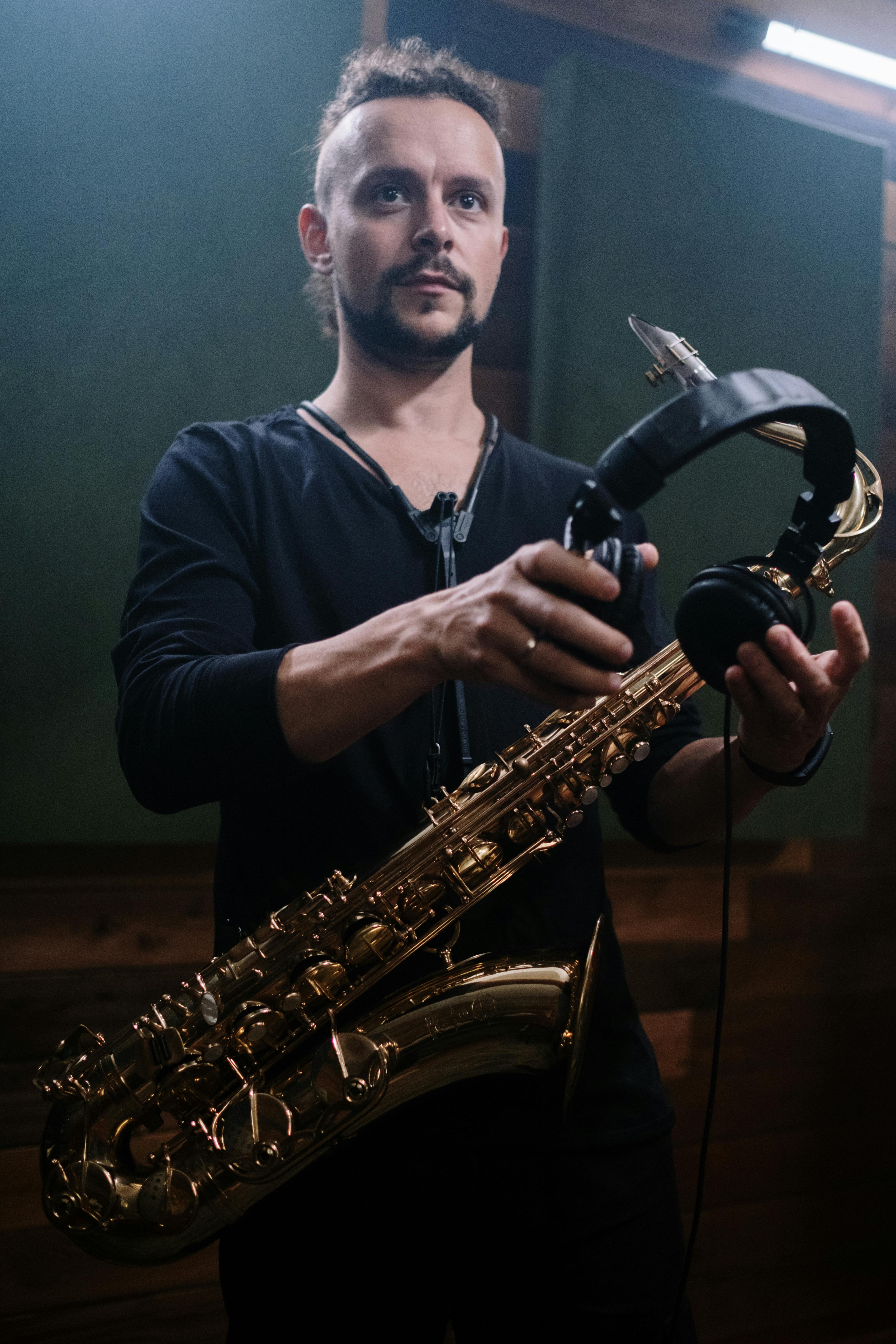 Man Holding Headphones and Saxophone · Free Stock Photo