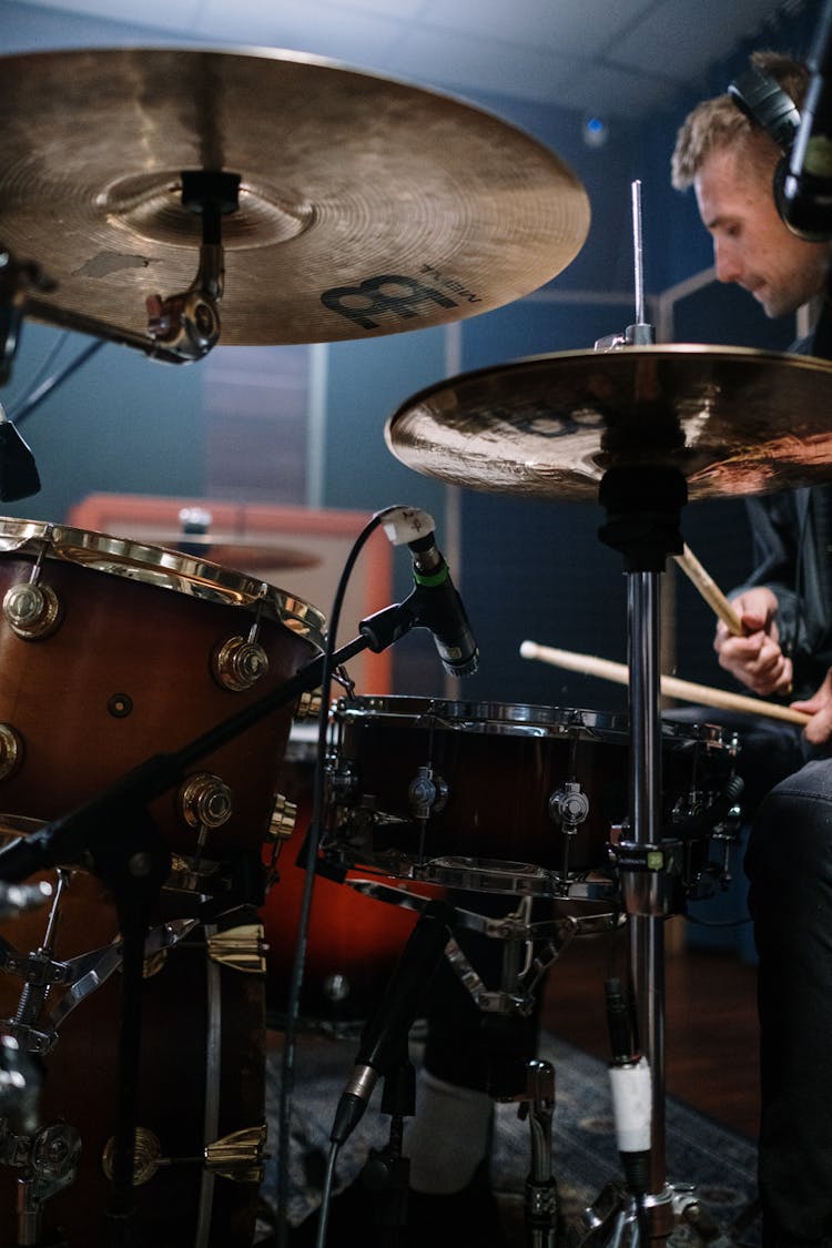 Man Wearing Headphones Playing Drum Set