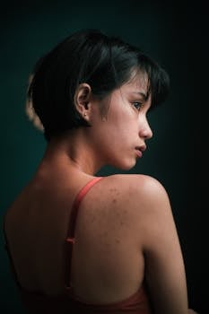 A thoughtful young woman with short dark hair, captured in a serene and moody portrait.
