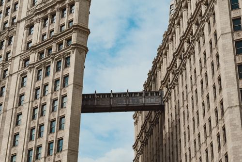 Free From below of high rise buildings with connecting bridge above street in cloudy day Stock Photo