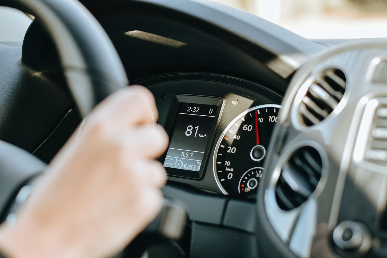 Fahrerperspektive auf Lenkrad und Anzeigeinstrumente bei Tageslicht.