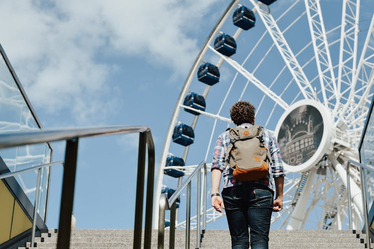 Man Standing On Stairs Near Ferris Wheel