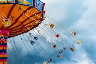 From below of colorful chain carousel located in amusement park in cloudy day