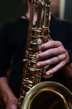 A musician plays the saxophone, focusing on hands and brass instrument