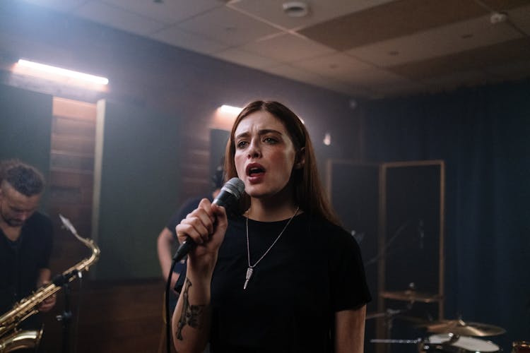 Young Woman Singing In Microphone With Band