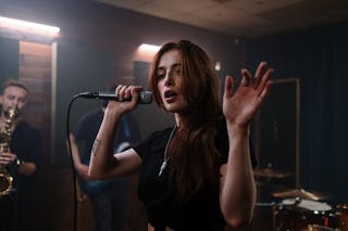A Woman in Black Shirt Holding a Mic and Singing