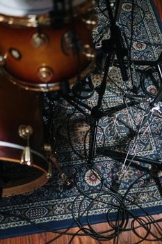 Aerial view of drum kit setup with cables and stands on a decorative rug.