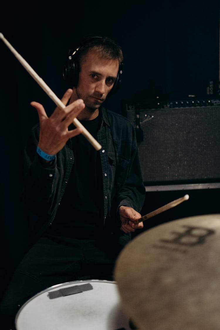 A Man Wearing Headphones Holding Drumsticks