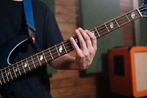 Free Musician playing a bass guitar indoors with focus on hand and strings. Stock Photo