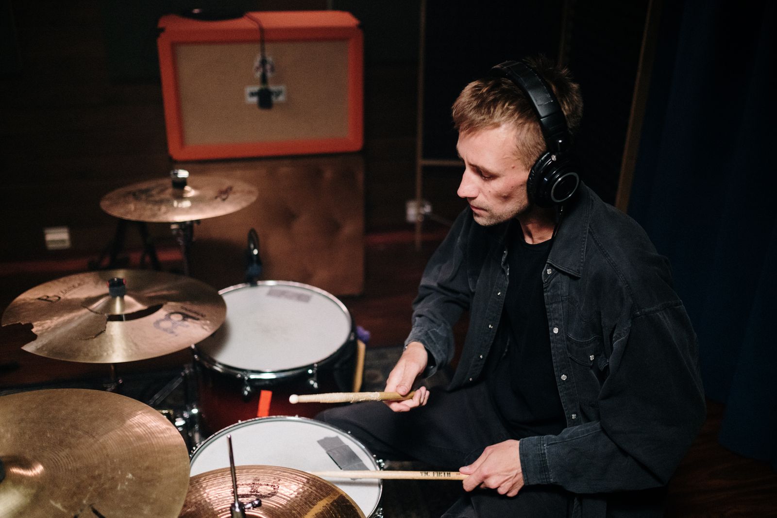 Young drummer practising with headphones on an electronic drum kit in a music studio