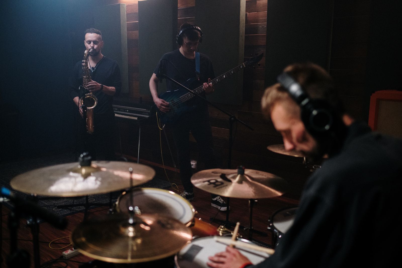 Band with saxophone and drums rehearsing in a dark studio