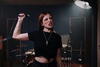 Woman in Black T-shirt and Black Denim Shorts Singing on Stage