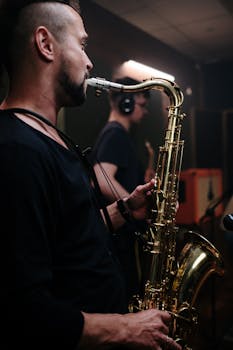 Musician playing saxophone during a live recording session in a dimly lit studio.