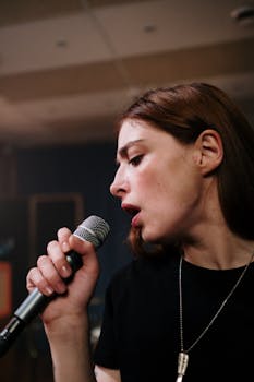 A passionate female vocalist performing with a microphone during a rehearsal indoors.