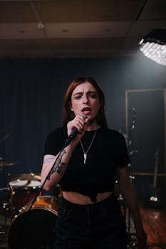 A passionate female singer performing in a studio with a band setup in the background.