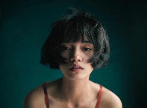 Moody portrait of an Asian woman with short hair, capturing a thoughtful and serene expression.