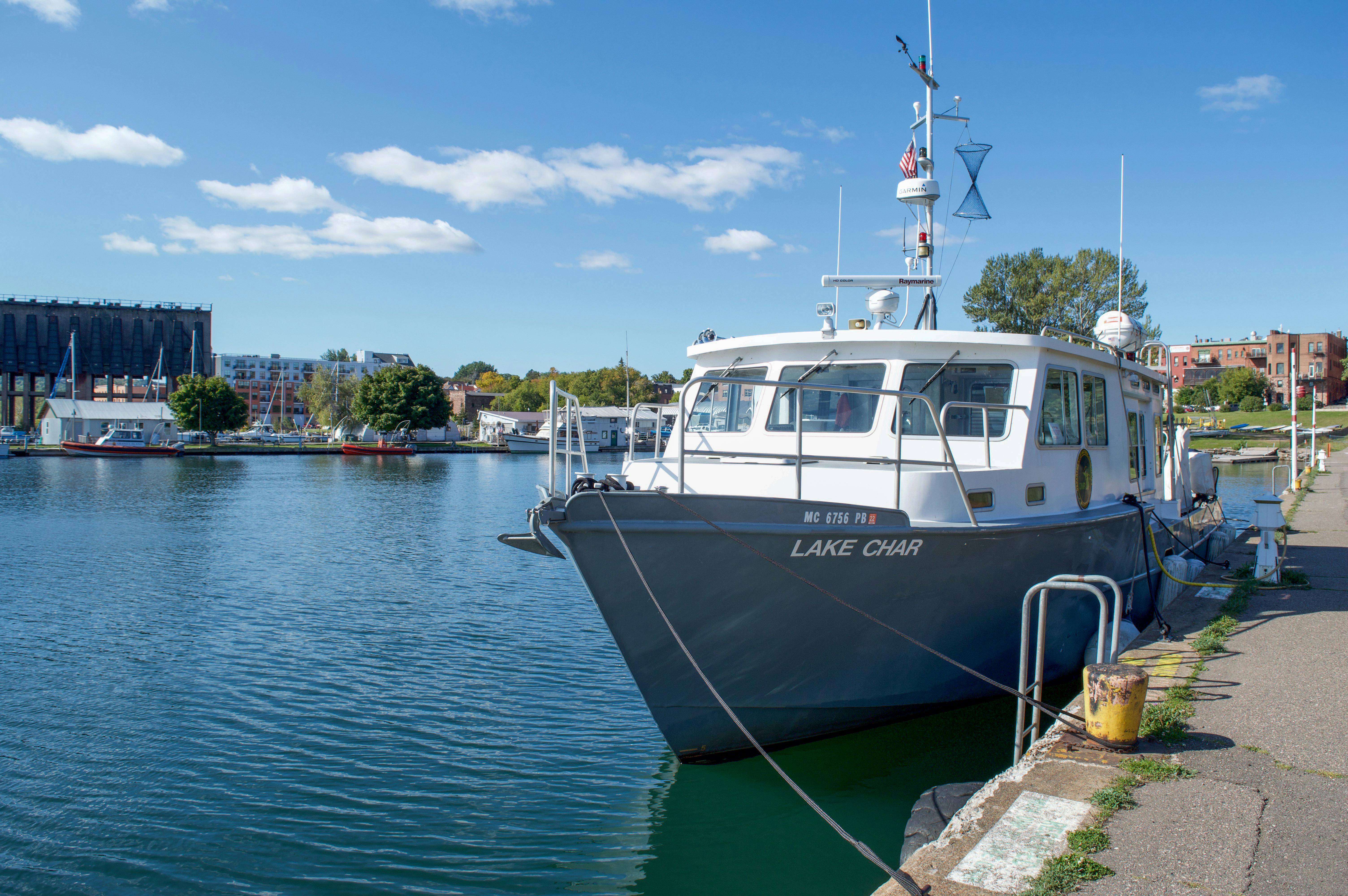A serene view of a boat moored at a harbor under a clear blue sky on a summer day.