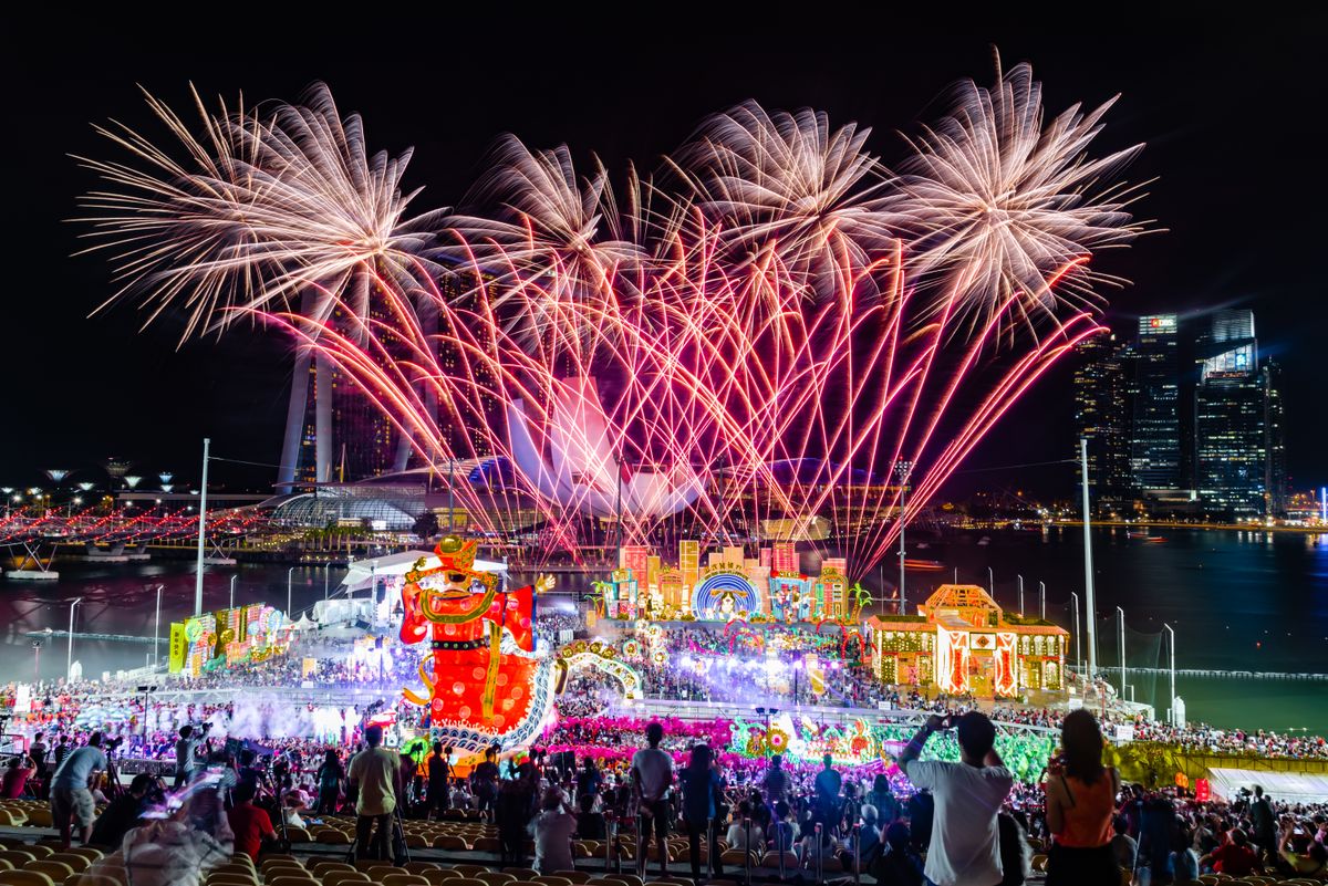 Multidão observa fogos coloridos à noite em uma celebração de Ano-Novo