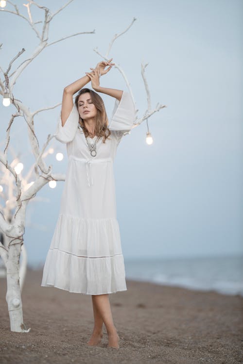 Woman in White Long Sleeve Dress Standing on Seashore