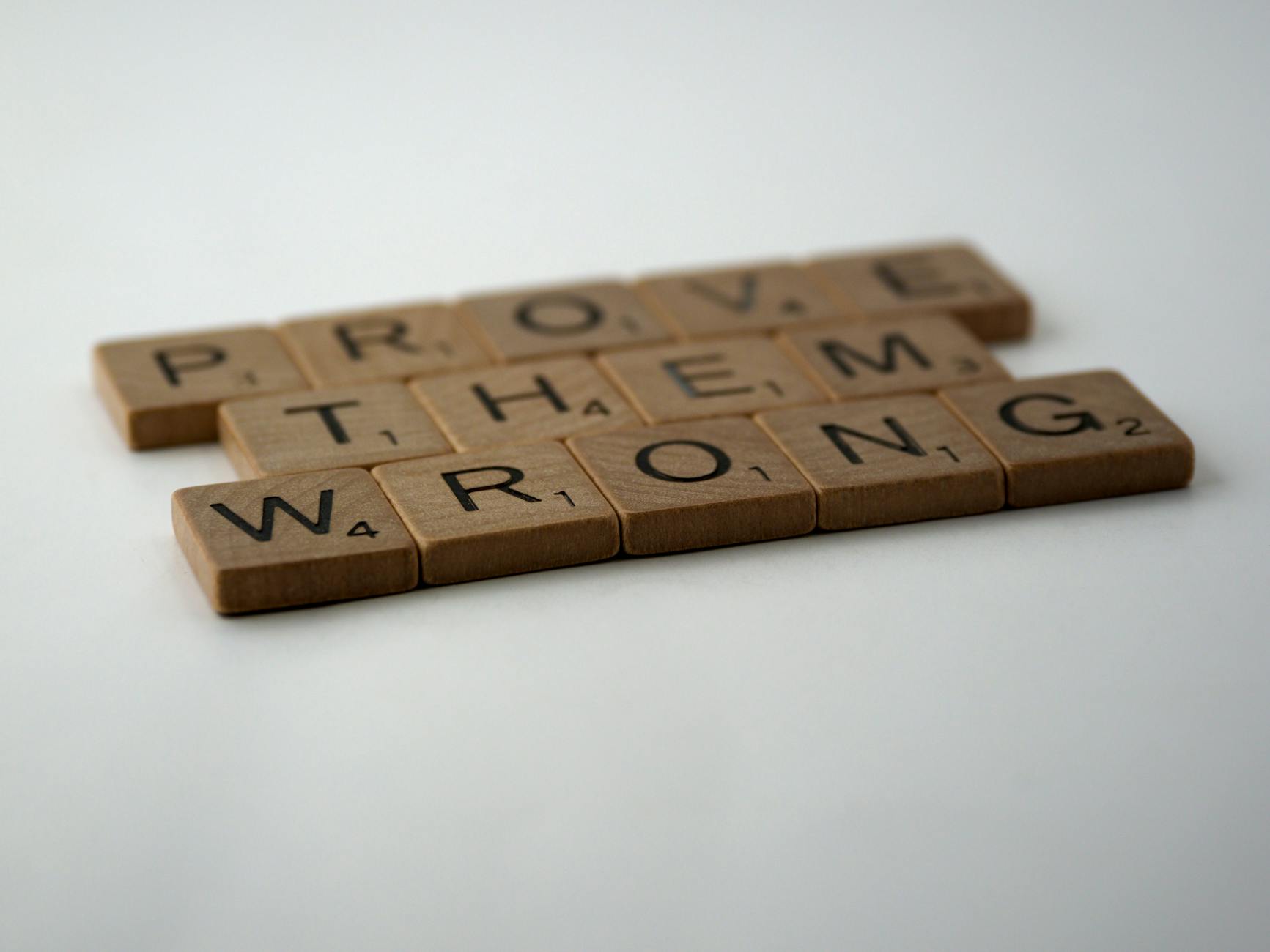 Scrabble tiles spelling 'Prove Them Wrong' on a white background, conveying motivation.