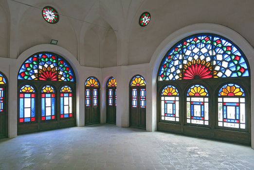 Colorful stained glass windows in a historic building with high arches and ornate designs.