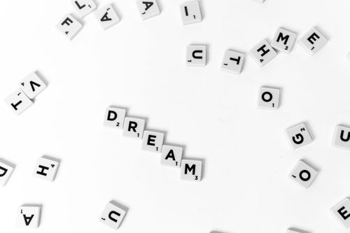 Free White background with Scrabble tiles spelling "Dream" amidst scattered letters. Stock Photo