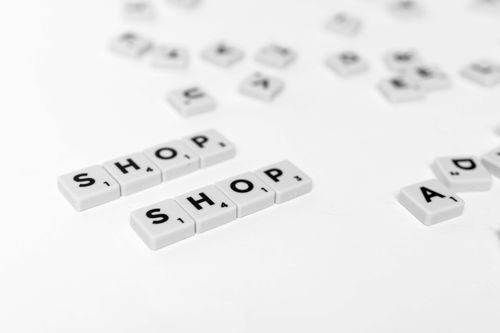 Free Close-up of scattered letter tiles spelling 'SHOP' on a clean white background. Stock Photo