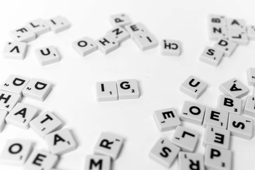 Black and white flat lay of scattered Scrabble tiles on a white surface.