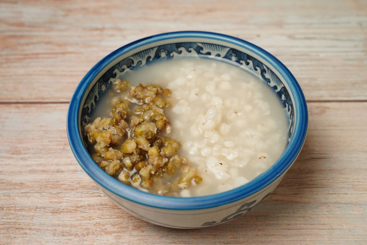 Bowl of soft white rice congee with a mound of cooked mung beans