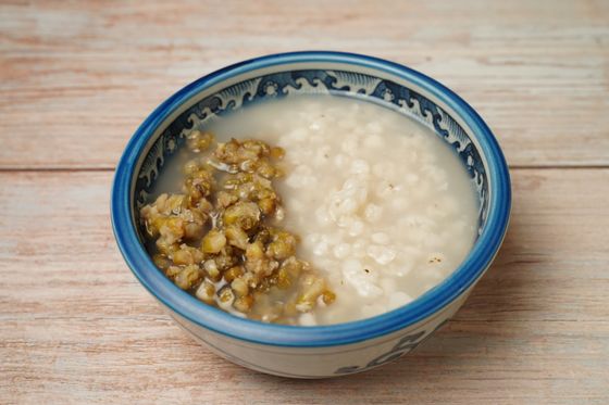 Bowl of soft white rice congee with a mound of cooked mung beans