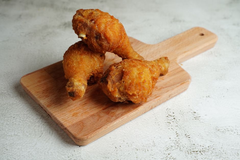 Golden fried chicken drumsticks placed on a wooden cutting board, perfect for a hearty meal.