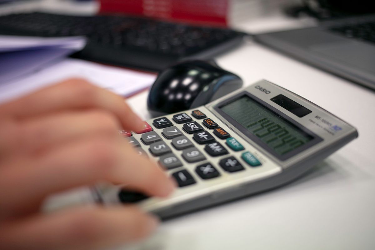 Main utilisant une calculatrice sur un bureau