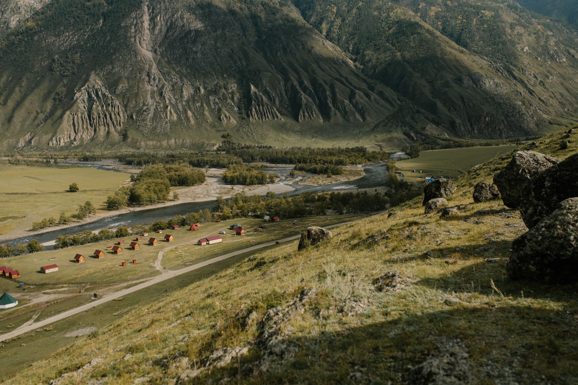 Explore a picturesque mountain valley with charming rustic cabins and lush greenery.