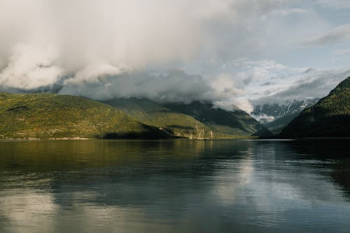 Free A Lake Beside the Mountains Under the Cloudy Sky Stock Photo