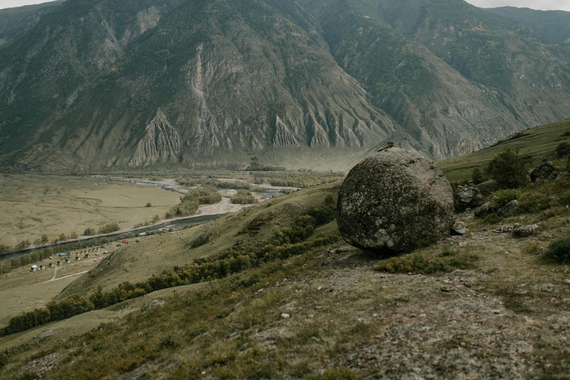 Captivating view of a vast mountainous landscape featuring a prominent boulder in the foreground.