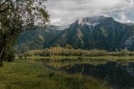 宁静的山景与湖泊，倒映着多云天空下的景色