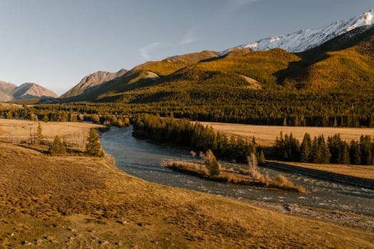 A scenic view of a mountain river surrounded by autumn foliage under a clear sky.