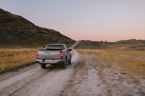 A Silver Pickup Truck Driving on Dirt Road