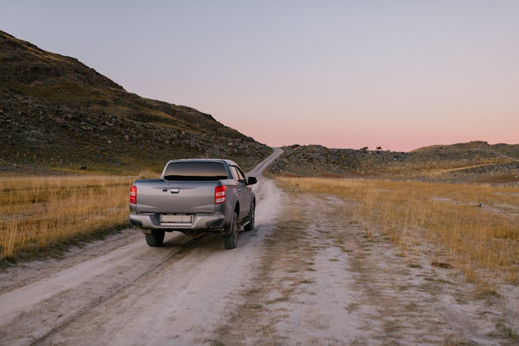 A Silver Pickup Truck Driving On Dirt Road