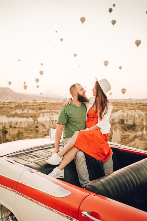 Positive young couple hugging while sitting together in old fashioned cabriolet among balloons in Turkey